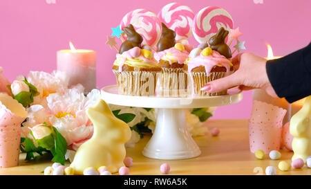 Easter theme candy land drip cupcakes decorated with chocolate bunnies in party table setting. Stock Photo