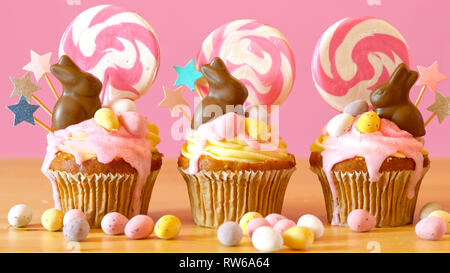 Easter theme candy land drip cupcakes decorated with chocolate bunnies in party table setting. Stock Photo