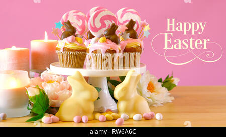 Easter theme candy land drip cupcakes decorated with chocolate bunnies in party table setting. Stock Photo