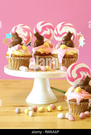 Easter theme candy land drip cupcakes decorated with chocolate bunnies in party table setting. Stock Photo
