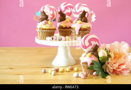 Easter theme candy land drip cupcakes decorated with chocolate bunnies in party table setting. Stock Photo