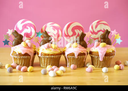 Easter theme candy land drip cupcakes decorated with chocolate bunnies in party table setting. Stock Photo