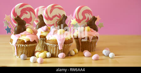 Easter theme candy land drip cupcakes decorated with chocolate bunnies in party table setting. Stock Photo