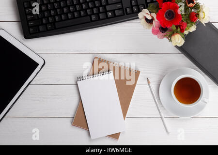 Empty notepad, cup of tea or coffee and office items on white desk, flat lay, top view nock up Stock Photo