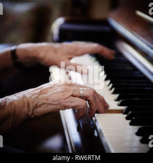 Ninety-two year old Jean McDougall plays the piano in her home. Her beautiful textured hands fly across the keys of the piano. Stock Photo