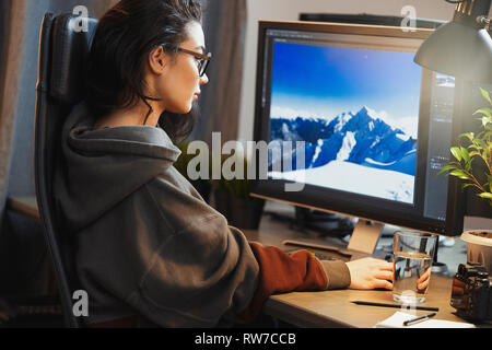 Young attractive woman freelancer designer working on pc at home. Concept of freedom and creativity. Home office. Casual dress. Stock Photo