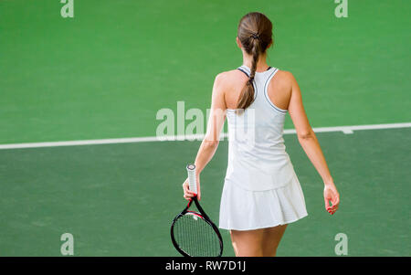 back view of a female tennis player with a racket in action Stock Photo