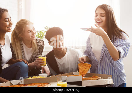 Girl taking photo of pizza, spending time with friends Stock Photo