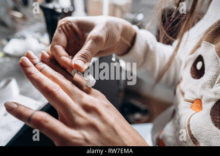 Client trying ring sizes on hand in jewelry workshop Stock Photo