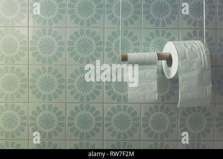 Two rolls of toilet paper on diy holder in a bath, light-blue tiles wall. Soft filtered, faded, vintage Stock Photo