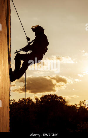 Silhouette of police officer during rope exercises with weapons. Stock Photo