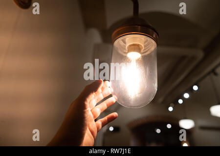 Hand reaching for a vintage light bulb. Stock Photo