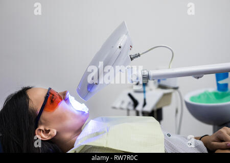Teeth whitening lamp ultravioleta. The girl on reception at the dentist for teeth whitening. The concept of dental care.