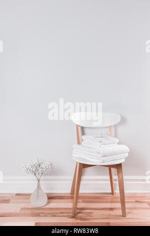 White terry towels on a chair in a bright interior decorated with Baby's Breath flowers. Stock Photo