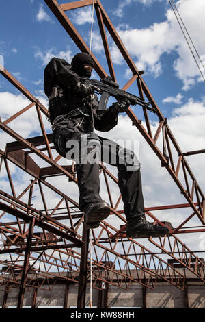 Special forces operator rappelling with weapons during an assault. Stock Photo