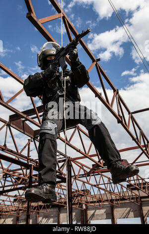 Special forces operator rappelling with weapons during an assault. Stock Photo