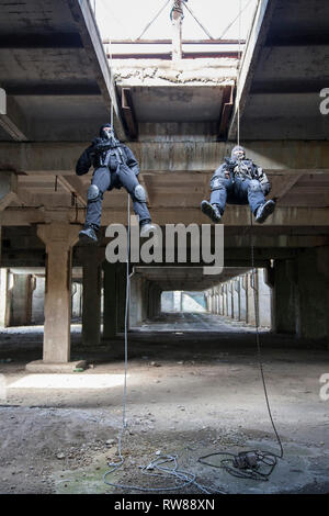 Special forces operators during assault rappelling with weapons. Stock Photo