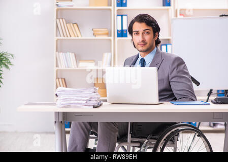 Young handsome employee in wheelchair at the office Stock Photo