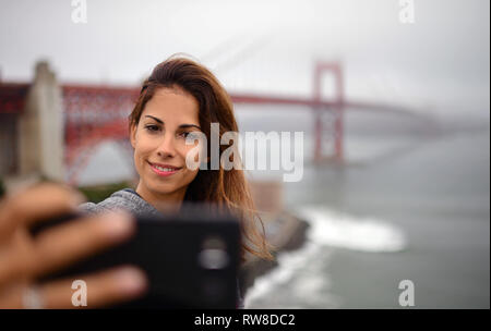 Young woman takes a selfie with Golden Gate Bridge, San Francisco. Stock Photo