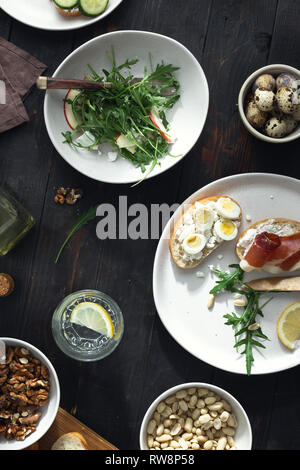 Healthy lunch on dark wooden background top view. Variety sandwiches and arugula salad for breakfast, appetizers, snack Stock Photo
