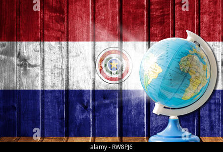 Globe with a world map on a wooden background with the image of the flag of Paraguay. The concept of travel and leisure abroad. Stock Photo