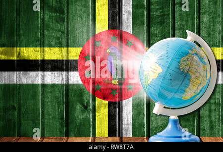 Globe with a world map on a wooden background with the image of the flag of Dominica. The concept of travel and leisure abroad. Stock Photo