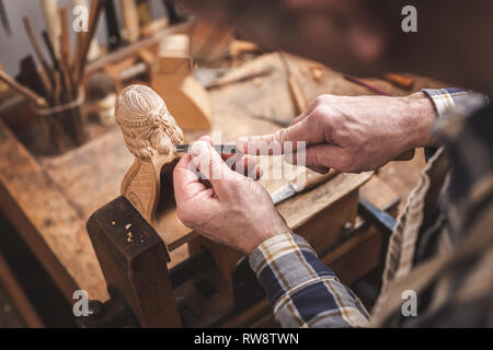 Wood sculptor at a workbench carving a wooden figure Stock Photo