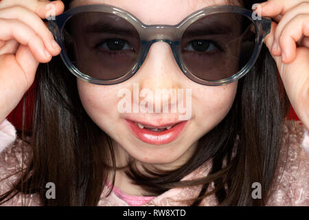 Young girl trying on her mums sunglasses Stock Photo