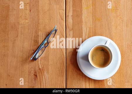 White cup of coffee and eyeglasses on Detailed textured wooden table view from above Stock Photo