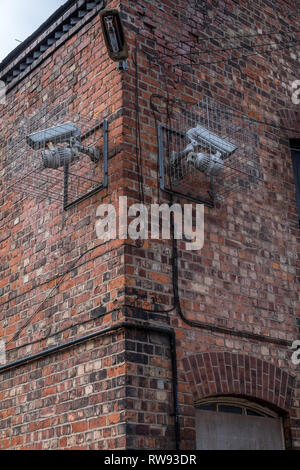 Two Security cameras on the THE END OF A BUILDING BOTH POINTING IN DIFFERENT DIRECTIONS Stock Photo