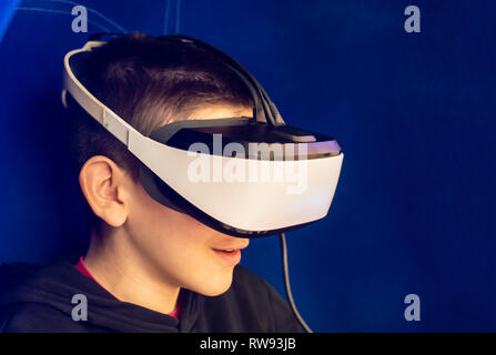 Child watching movie with VR glasses. Blue illuminated cabin with joysticks. Special effects. Technology and entertainment concept with virtual realit Stock Photo