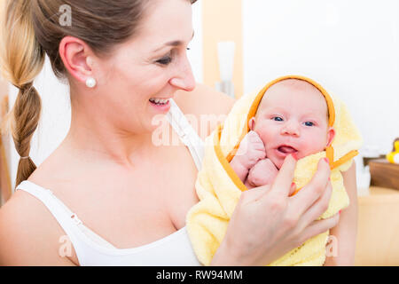 Smiling mother carrying her baby wrapped in towel Stock Photo