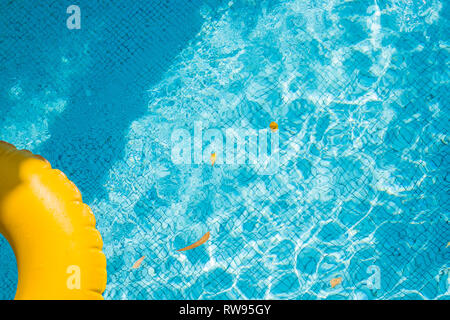 floating ring on blue water swimpool with waves reflecting in the summer sun. Lazy river.Water pool with yellow pool float ring.Summer vacation or Stock Photo