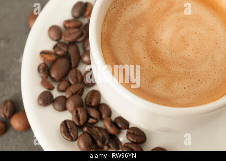Detail of cup of coffee with perfect cream and coffee beans on gray background Stock Photo