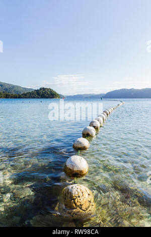Line of white buoys sit on the waters top of Lake in New Zealand. Stock Photo