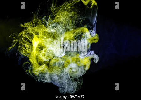 Thick colorful smoke of  green, blue on a black isolated background. Background from the smoke of vape Stock Photo