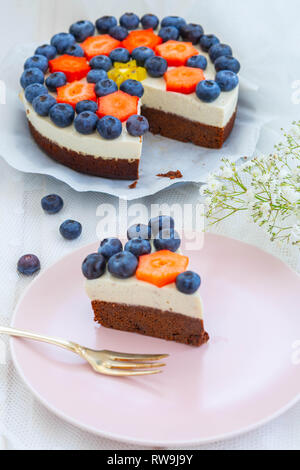 vegan cheesecake with chocolate cake base, vegan walnut fresh cheese, vanilla pulp and fresh fruits, blueberries, strawberries and kiwi fruit Stock Photo