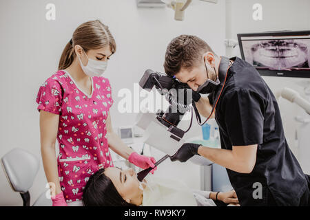 Close up of young man dentist taking picture of teeth of female patient in dental office. Stock Photo
