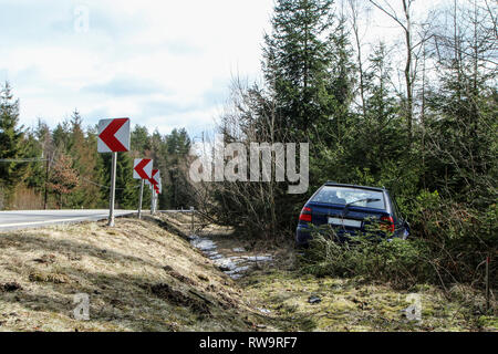 A car destroyed during the traffic accident. The car is abandoned and stands by the road in the trees. Stock Photo