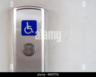 Elevator button with blue disabled people sign on stainless steel elevator panel on old and dirty white background with copy space. Elevator button fo Stock Photo