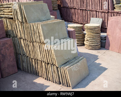 Rows and piles of square and round stone plates for garden decoration. Stock Photo