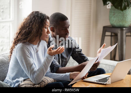 Concerned black couple read bills considering paperwork at home Stock Photo