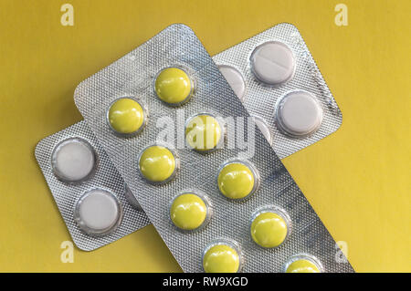 Yellow round pills in a package on a yellow background, close-up Stock Photo