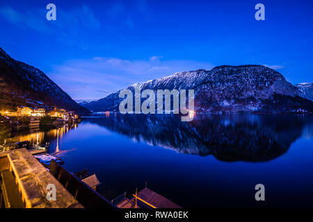 Slow exposure photo captured after sunset during blue hour over the crystal clear alpine lake at Hallstatt in Austria Stock Photo
