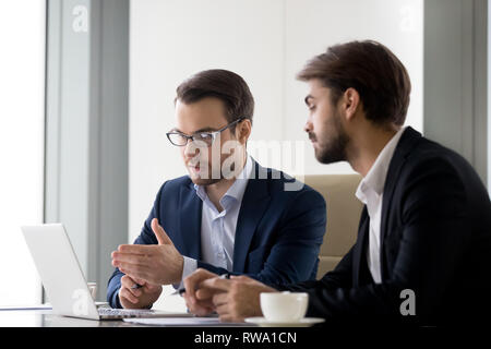Executive businessmen colleagues working together helping in teamwork on laptop Stock Photo