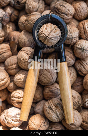 Nutcracker and lot of walnuts on table Stock Photo