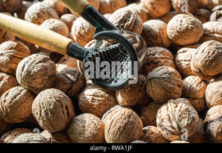 Nutcracker and lot of walnuts on table Stock Photo