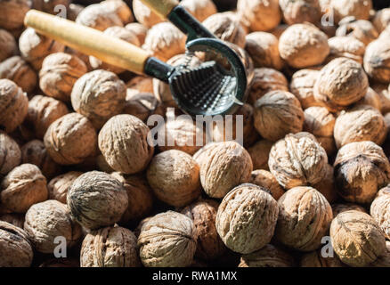 Nutcracker and lot of walnuts on table Stock Photo