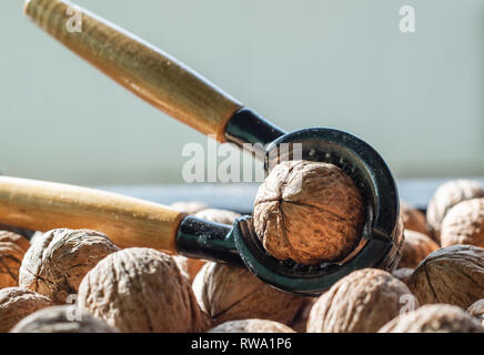 Nutcracker and lot of walnuts on table Stock Photo