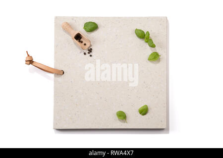 Concrete stone server with space for text on white background. Arranged basil leaves, wooden scoop and peppercorns. For restaurants, food magazines .. Stock Photo